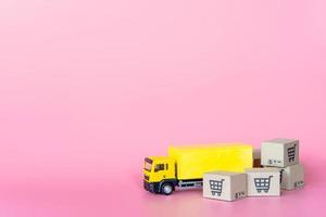 logística y servicio de entrega: camión de carga y cajas de papel o paquetes con el logotipo de un carrito de la compra sobre fondo rosa. servicio de compra en la web online y ofrece servicio a domicilio. foto