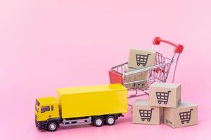 Logistics, and delivery service - Cargo truck, Red shopping cart and paper cartons or parcel with a shopping cart logo on Pink background. Shopping service on The online web and offers home delivery. photo