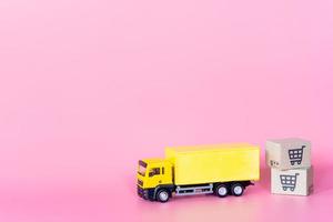 Logistics, and delivery service - Cargo truck and paper cartons or parcel with a shopping cart logo on Pink background. Shopping service on The online web and offers home delivery. photo