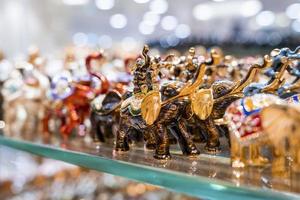 Various colorful elephant figurines display on shelf for sale in shop photo