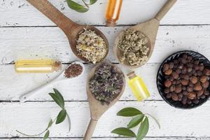 Dry herbs in wooden spoons. Dry rosehip. Essences in vintage glass bottles. Alternative medicine. Flat lay photo