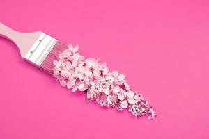 pincel con flores blancas sobre fondo rosa. concepto creativo de magia de primavera foto