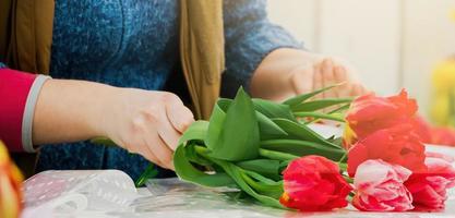 Woman florist makes bouquet of fresh tulips. photo