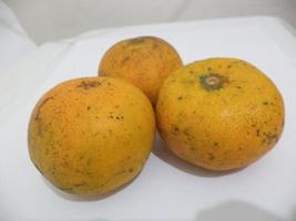 three oranges on a white table photo