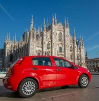 coche rojo estacionado en piazza duomo en milán foto