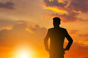 silueta de un hombre de negocios con un camino de recortes de pie mirando la puesta de sol por la noche foto