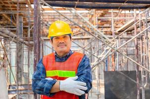 Engineer man worker checking and planning project at construction site, Smiling man with arms crossed over blurred background