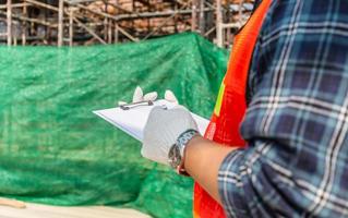 Close up of worker man holding clipboard checklist at construction site photo