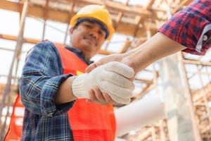 Close up of engineer and worker handshake with blurred construction site, Success and Teamwork concept photo