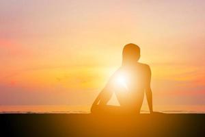 Silhouette of young woman with clipping path practicing yoga relaxing exercise at sunset photo