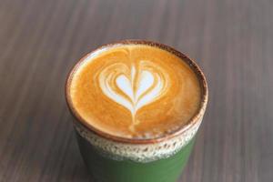 enfoque selectivo del café con leche caliente en taza de cerámica sobre fondo de mesa de madera borrosa foto