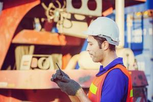 Foreman in hardhat and safety vest talks on two-way radio control loading containers box from cargo photo