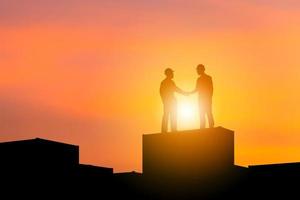 silueta de hombre ingeniero de negocios con apretón de manos de ruta de recorte en contenedor de carga fondo de puesta de sol de cielo nocturno, concepto de equipo de éxito y felicidad foto