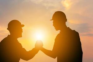 silueta de ingeniero de negocios hombre con trazado de recorte apretón de manos fondo de puesta de sol de cielo nocturno, concepto de equipo de éxito y felicidad foto