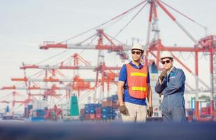 Engineer and Worker man in hardhat and safety vest checking control loading containers box from cargo, Teamwork concept photo