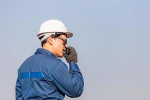 Foreman in hardhat and safety vest talks on two-way radio control loading containers box from cargo photo