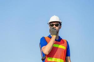 Foreman in hardhat and safety vest talks on two-way radio control loading containers box from cargo photo