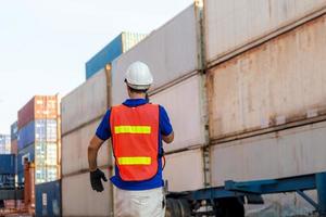 Foreman in hardhat and safety vest talks on two-way radio control loading containers box from cargo photo