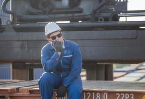 Foreman in hardhat and safety vest talks on two-way radio control loading containers box from cargo photo