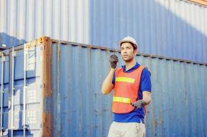 Foreman in hardhat and safety vest talks on two-way radio control loading containers box from cargo photo