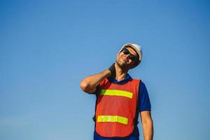 Factory worker holding painful shoulder with another hand, young man with neck pain photo