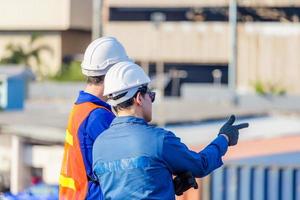 Worker man in hardhat and safety vest and foreman checking control loading containers box from cargo, Teamwork concept photo