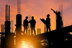 silueta de ingeniero y trabajador en el sitio de construcción, sitio de construcción al atardecer en el tiempo de la tarde. foto