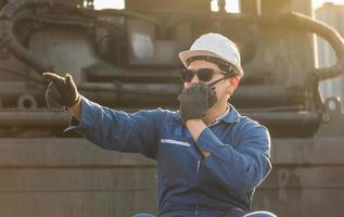 Factory worker man in hardhat and safety vest talks on two-way radio control loading containers box from cargo photo