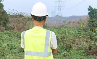 detrás de los ingenieros en uniforme y cascos están frente a los postes de alta tensión. foto