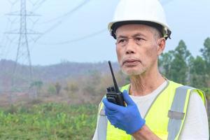 A senior engineer inspects a high-voltage power pole in a forested area. photo