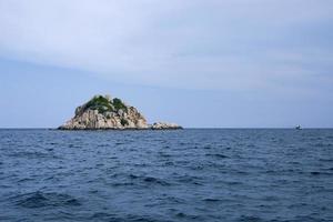 isla de roca y mar azul profundo en el golfo de tailandia foto