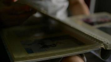 Woman's hand flipping pages of memory photo album in living room. video