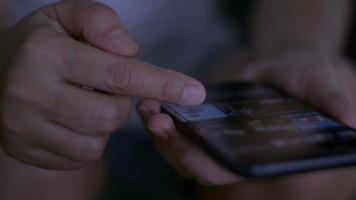 Woman's hand browsing movie video in the internet library to select film online.