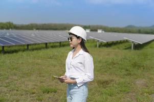 Female engineer wearing helmet in Photovoltaic Cell Farm or Solar Panels Field, eco friendly and clean energy.