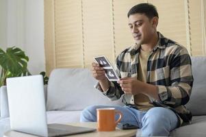 Young father holding ultrasound photo of newborn baby, maternity and family concept