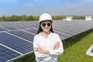 Female engineer wearing helmet in Photovoltaic Cell Farm or Solar Panels Field, eco friendly and clean energy. photo