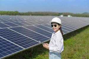 ingeniera con casco en granja de células fotovoltaicas o campo de paneles solares, energía ecológica y limpia.