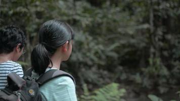 Asian teenage girl with backpack walking with her mother in tropical forest. video