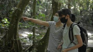 mãe usa máscara facial aconselhando sua filha adolescente a ver a bela natureza na floresta tropical. video
