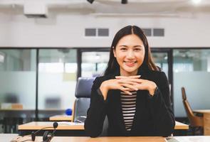 felicidad y sonriente joven hermosa mujer de negocios con auriculares, concepto de servicio de operador profesional foto