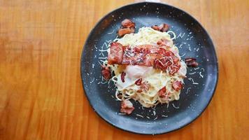 Carbonara spaghetti with onsen egg, crispy bacon, hard parmesan cheese and cream sauce. photo