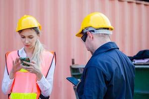 Engineer in the hard hat uses mobile phone, Industrial worker using mobile smartphone in industry containers cargo