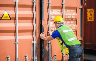 Engineer worker man in hardhat and safety vest checking containers box from cargo photo