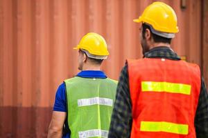 vista trasera del equipo de ingenieros y trabajadores con sombrero duro comprobando la carga de los contenedores foto