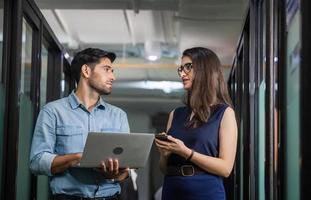 Businessman holding laptop and walking discusses work with female team, Young business team of coworkers meeting in creative office photo