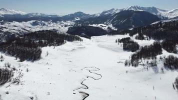 vue aérienne étonnante d'une rivière tourbillonnante dans les montagnes pendant la journée ensoleillée d'hiver. tout est blanc et couvert de neige. belle destination de voyage d'hiver. video