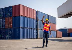 Worker man in hardhat and safety vest standing at containers cargo, Foreman control loading containers box from cargo photo