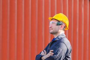 Factory worker man with clipping path smiling with arms crossed on blurred background photo