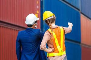 Engineer and worker team wearing protection face mask against coronavirus checking containers box from cargo, Logistic and teamwork concept photo