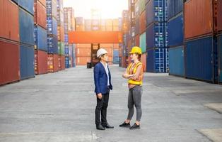 Engineer and foreman worker team in hardhat and safety vest control loading containers box from cargo photo